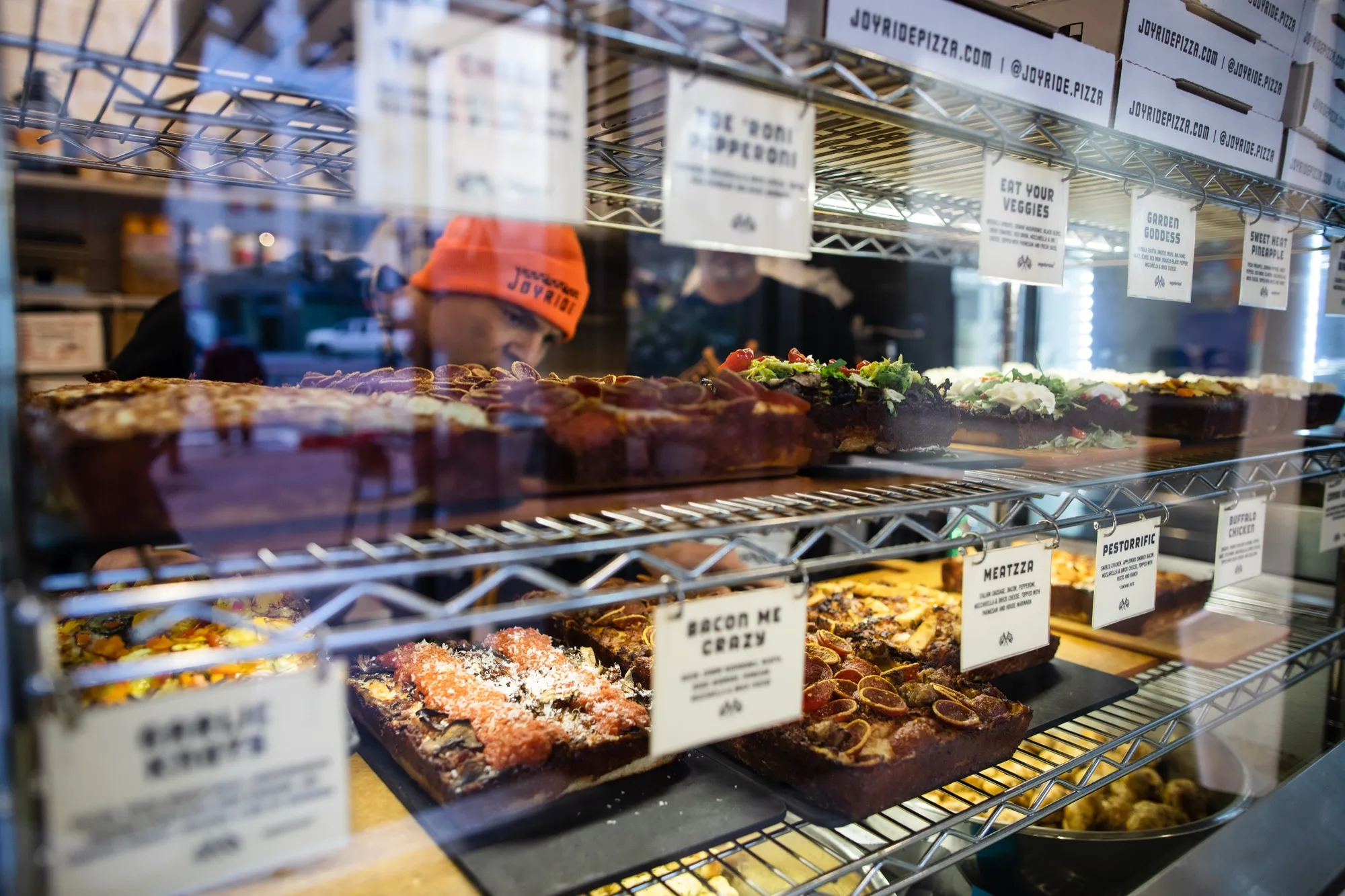 Case of hot Detroit-style square slices with menu tags at the Market Street counter