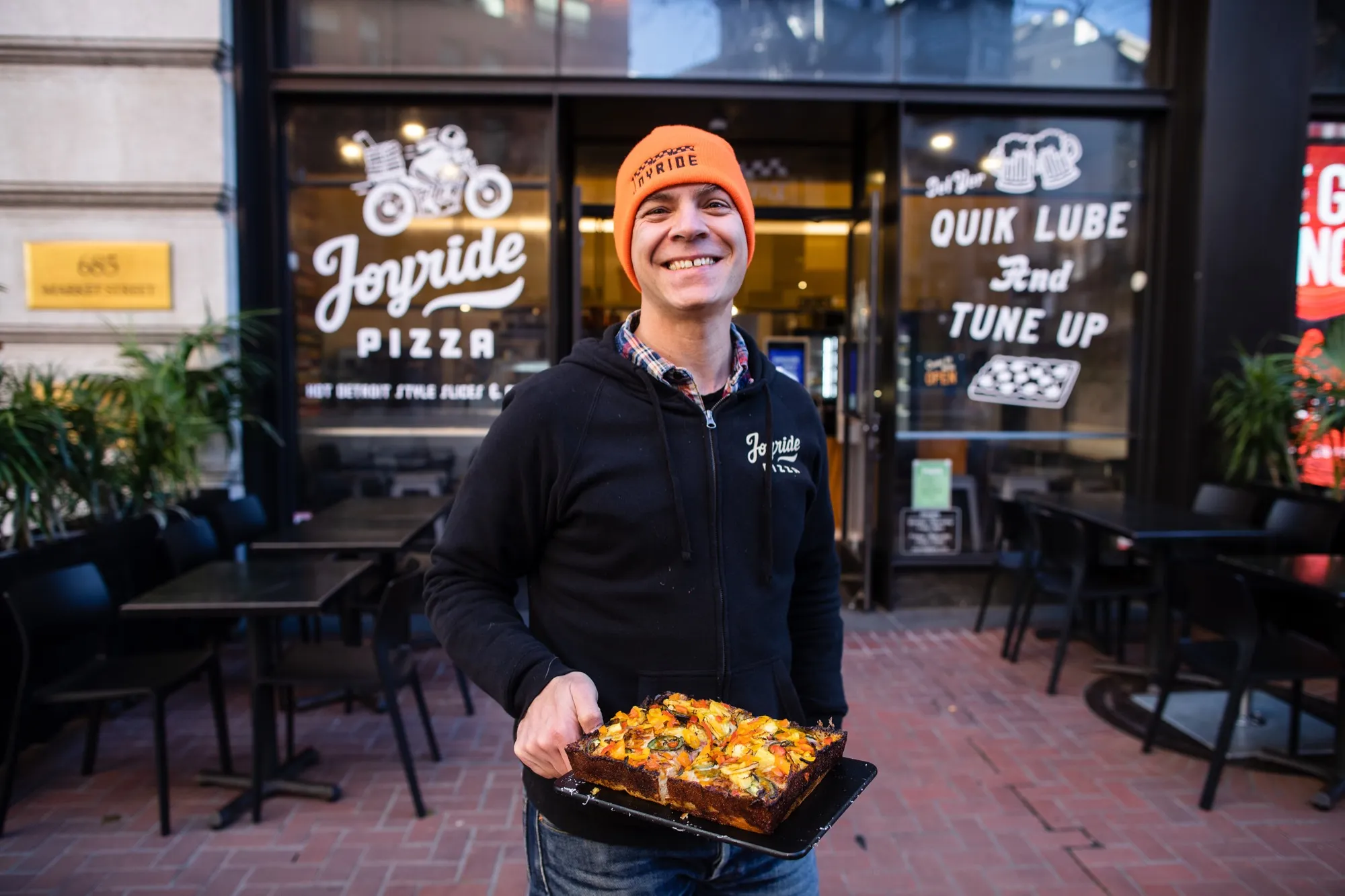 Joyride staffer holding a fresh Detroit-style veggie square outside the Market Street shop